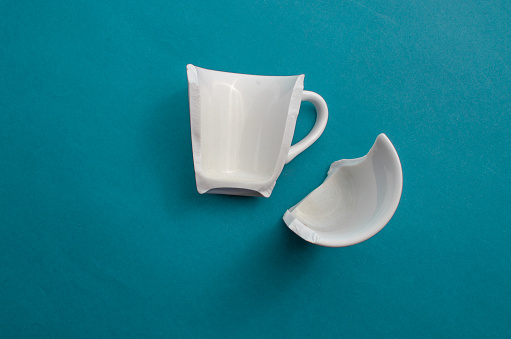 Cup broken in half highlighted on a blue background, symbolizing a moment of rupture.