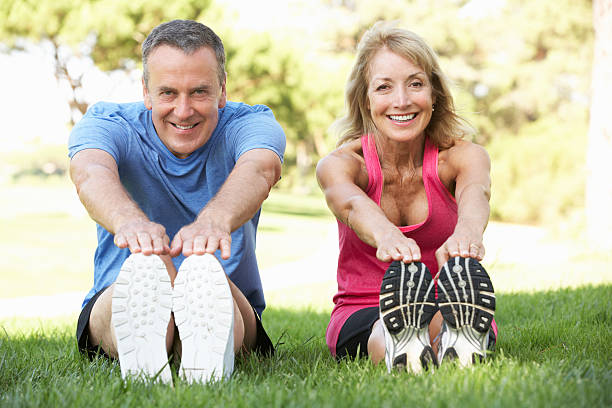 istock Mature couple stretching in grassy park 157689528
