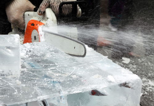 Unrecognized person cutting ice block in preparation of ice sculpture in Toronto, Ontario, Canada