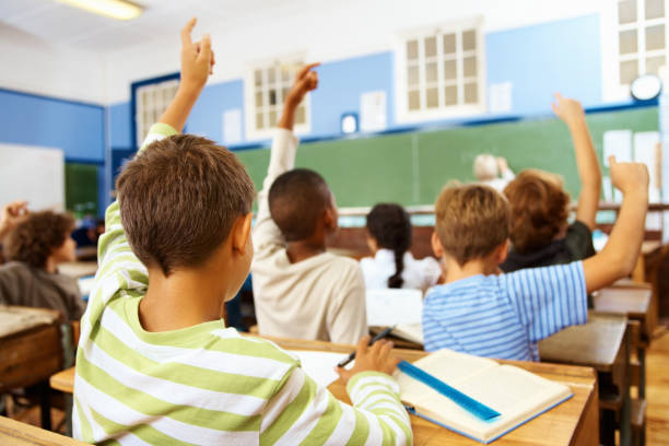 istock Rear view of schoolboy in classroom with hands raised 157691937