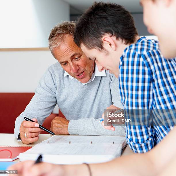 Primo Piano Del Maschio Studente Con Insegnante Aiutando La Sua Scuola Lavoro - Fotografie stock e altre immagini di Aula