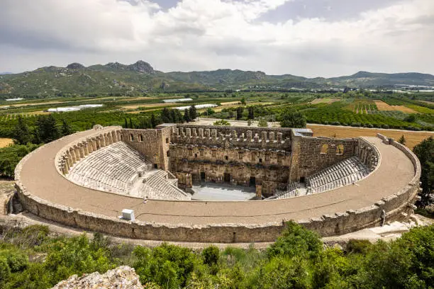 A Roman theatre, at Aspendos surrounded with green agricultural fields and mountain range in the spring, Antalya, Turkey