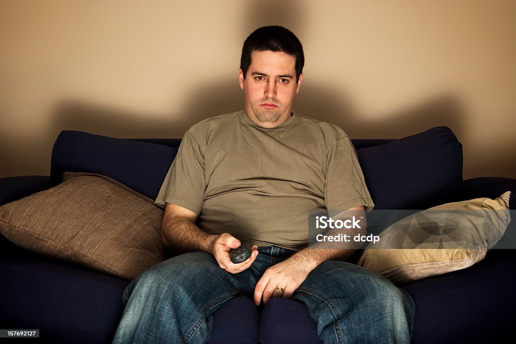 Marre, lazy, en surpoids homme se dresse sur le canapé-lit - Photo de Paresse libre de droits