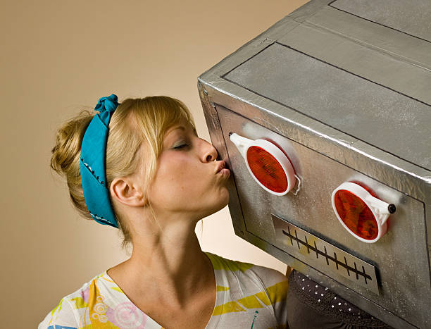 Close-up of woman in striped shirt kissing robot stock photo