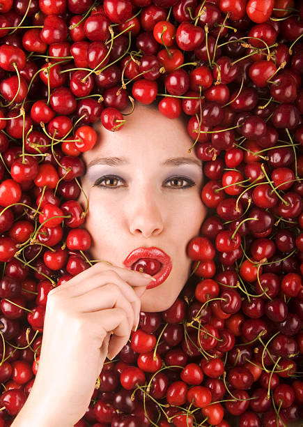 Cherry Girl Face of beautiful young woman among red fresh cherries tasting cherry eating human face stock pictures, royalty-free photos & images