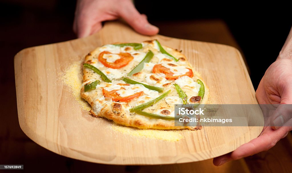 pizza vegetariana viene servito su una racchetta di legno - Foto stock royalty-free di Adulto