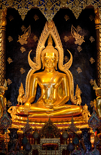 Phra Buddha Chinnarat at Wat Phra Si Ratana Mahathat, Phitsanulok Province, Thailand. This beautiful golden Buddha image resides in the main hall of the temple, which is open to the public. It is regarded as one of Thailand's most revered Buddha images, perhaps second to The Emerald Buddha which resides in Wat Phra Kaew in the grounds of the Grand Palace in Bangkok. This image dates from the 14th century and thousands of people visit the temple every day to pay respect to the Lord Buddha.