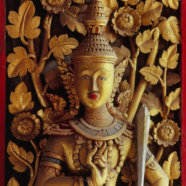 Decorative carved antique wood figure on a Thai Buddhist temple window.