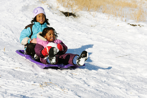 Caucasian family, parents with their children sledding on the hill with sled, during winter holiday
