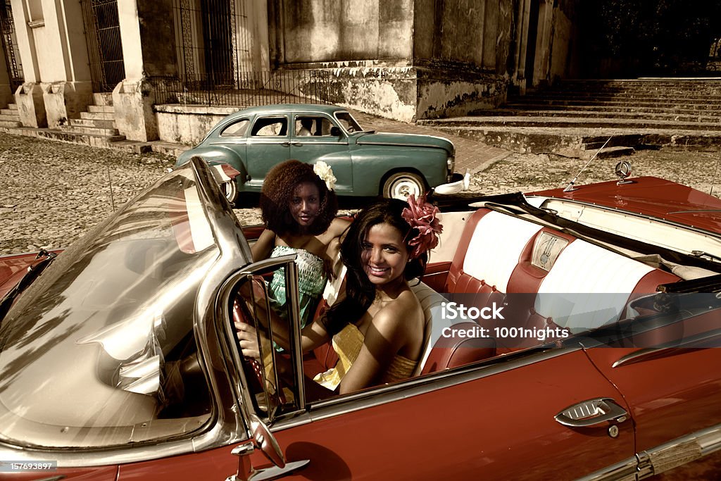 Two beautiful women posing with a red car Two beautiful women posing with a old red car at the streets of Cuba Adult Stock Photo