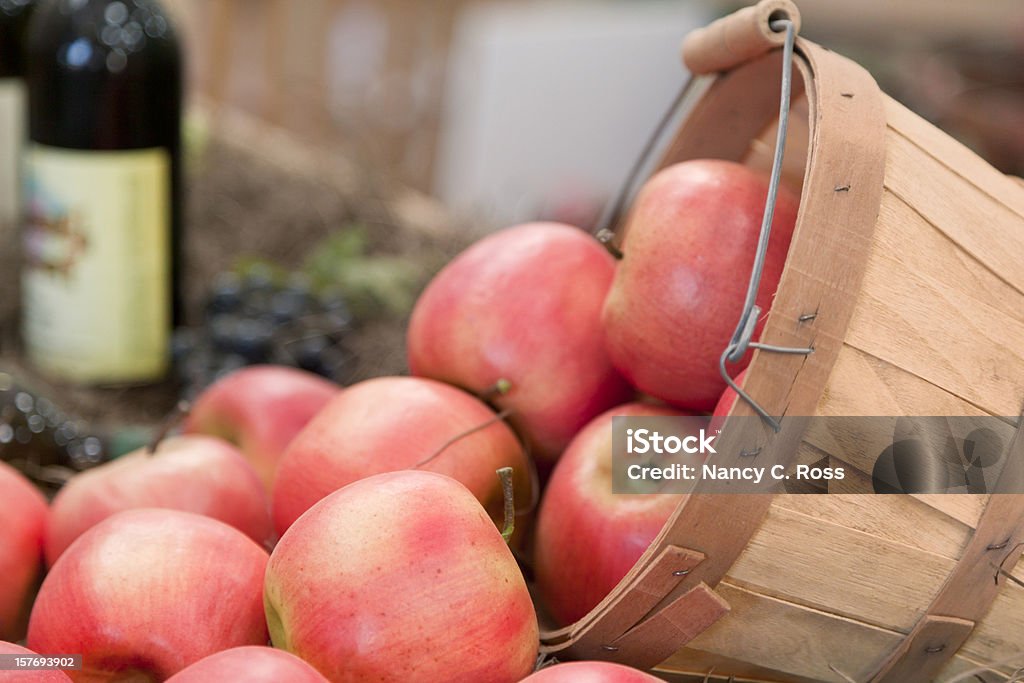 Pommes débordant de panier, bouteille de vin en arrière-plan - Photo de Agriculture libre de droits