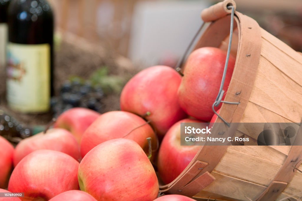 Mele che riempiono cestello, bottiglia di vino sullo sfondo - Foto stock royalty-free di Abbondanza