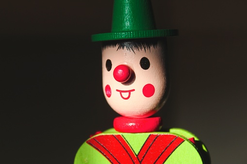 A wooden clown toy with a green hat and a red nose