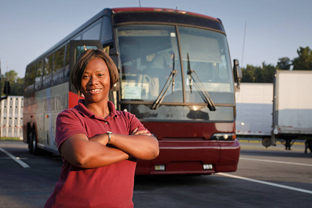 Female bus driver standing in front of a passenger bus 