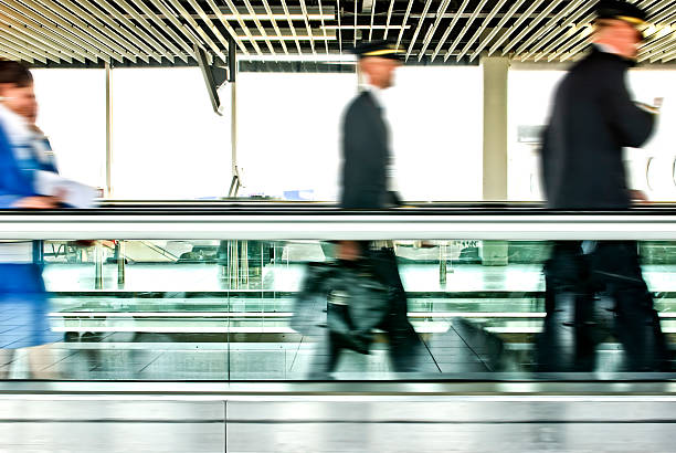 airline staff blurred motion of unrecogniscible airplane staff on a Moving Walkway travolator stock pictures, royalty-free photos & images