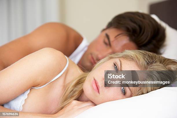 Young Couple In Bed Man Asleep And Woman Looking Worried Stock Photo - Download Image Now