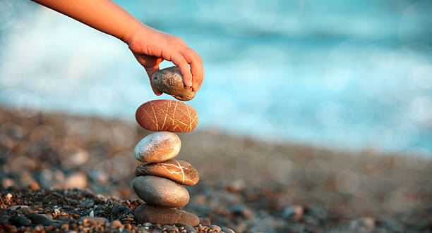 child playing on beach close up shot of child hand playing with stones on beach. stability stock pictures, royalty-free photos & images