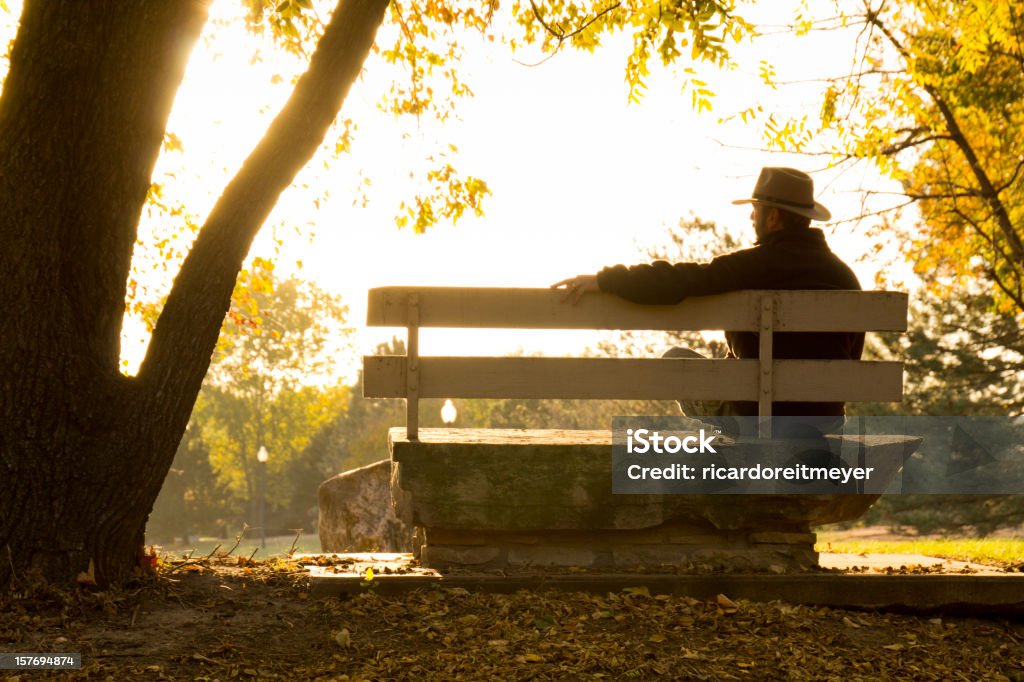 Adulto maduro homem situa-se estrategicamente no banco de parque no outono nos EUA - Foto de stock de Terceira idade royalty-free