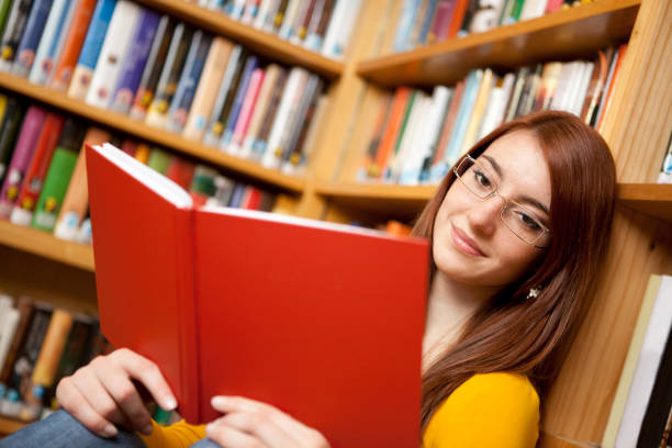 istock Attractive female reading book in library 157694945