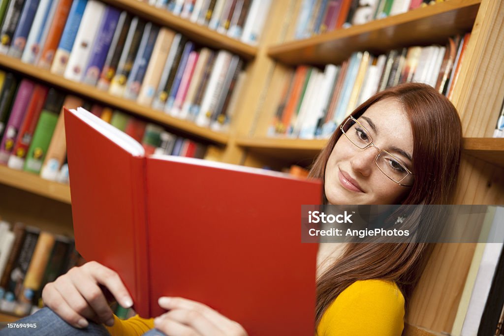 Atrakcyjna kobieta czytanie książki w bibliotece - Zbiór zdjęć royalty-free (16-17 lat)