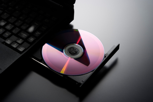 Inserting a CD into a laptop computer with opened and loaded dvd drive.