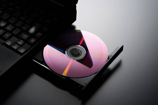 Inserting a CD into a laptop computer with copy space Inserting a CD into a laptop computer with opened and loaded dvd drive. dvd player stock pictures, royalty-free photos & images