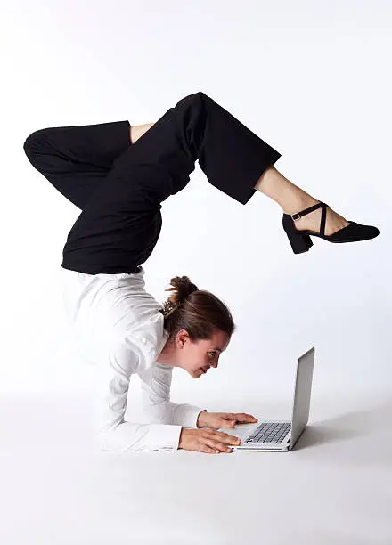 businesswoman in scorpion yoga pose, looking into laptop - on white background
