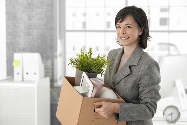 Smiling business woman holding a box of office items stock photo