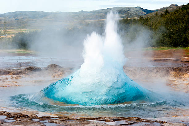 Multicolored strokkur with mountain range detail shot of hot spring strokkur on iceland in the first second of eruption; geothermal region in the golden circle (Gullfoss, Thingvellir, Geysir) of iceland iceland image horizontal color image stock pictures, royalty-free photos & images
