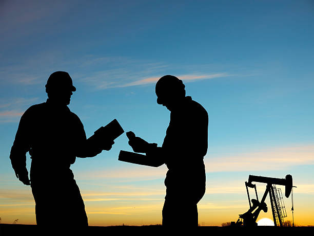 2 silhouettes of oil workers and a pump