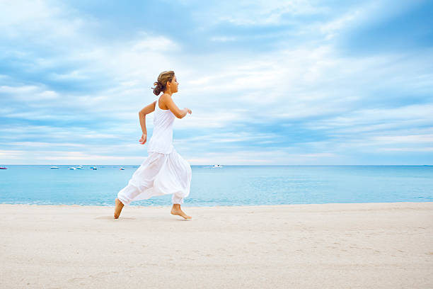 若い女の子は、ビーチでのランニング - zen like sea horizon over water blurred motion ストックフォトと画像