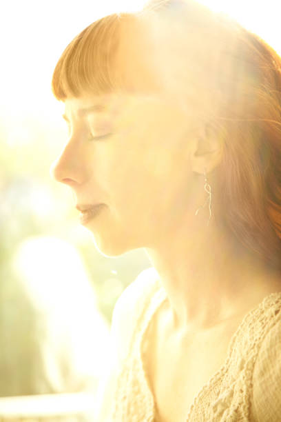 istock Redhead woman backlit by sun with eyes closed 157696645