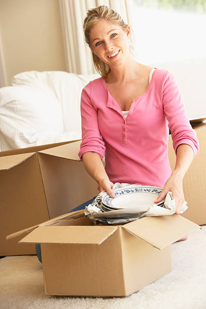 istock Young Woman Moving Into New Home Unpacking Boxes 157697122