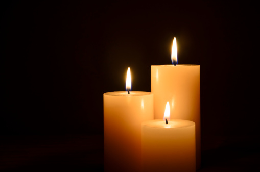 Three lit candles isolated on a black background.