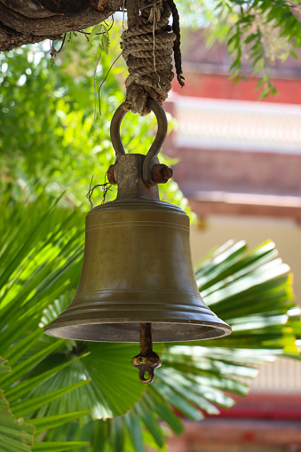 Many metallic bells hanging in a row on wooden pillars outside in thai buddhist temple. Lined with many beautiful bells, Thai temple bell which believe that who knock this bell will get the good luck, Image with shallow depth of field, No focus, specifically.