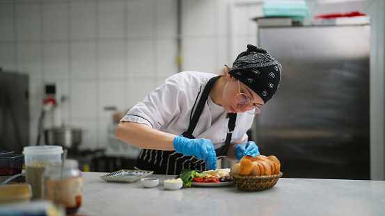 A young woman is working and preparing food in a commercial kitchen.