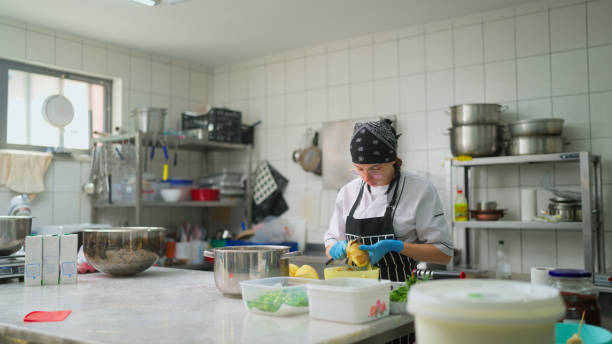 istock Young woman working and peeling potatoes in commercial kitchen 1577020981