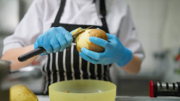 mujer joven trabajando y pelando papas en cocina comercial - commercial kitchen bakery front view baking fotografías e imágenes de stock