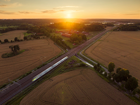 A train in motion on a railway through a rural landscape at sunset in Uppland, Sweden.