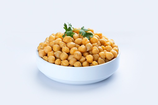 Cooked chickpeas in white bowl isolated on white.