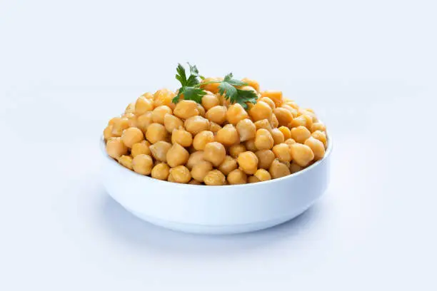Photo of Cooked chickpeas in white bowl isolated on white.