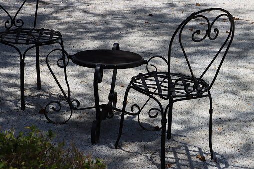 Stock photo showing close-up of al fresco dining area with wrought iron furniture with decorative scrolls.