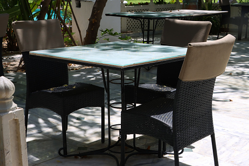 Stock photo showing close-up view of patio al fresco dining area with rattan seating and marble topped table.