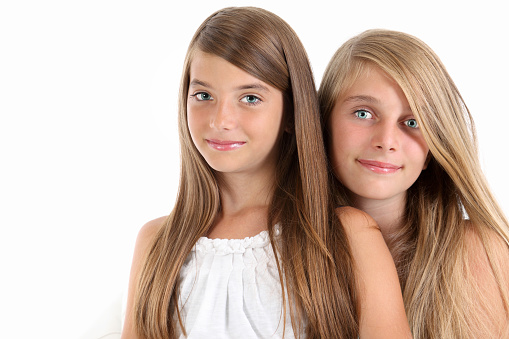 Two teenage girls posing in front of white background