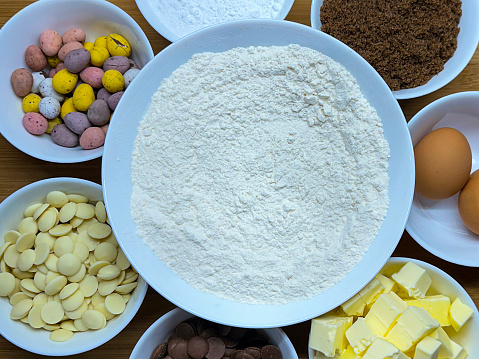 Stock photo showing close-up, elevated view of bowls containing dry baking ingredients to make Easter biscuits.