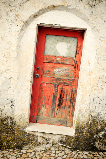 Antique weathered door with broken  glass and concrete wall.