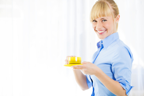 Portrait of an young business woman smiling, looking at camera and drinking coffee.
