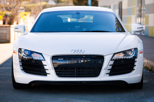 Dartmouth, Nova Scotia, Canada - October 24, 2012: An Audi R8 front view showing the Audi emblem in center of hood, and the world's first, all-LED headlights.  Vehicle is parked in the shade of a building which can be seen to the right of frame.  The Audi R8 is a mid-engined sports car that features a 4.2L V8 engine producing 420 HP.