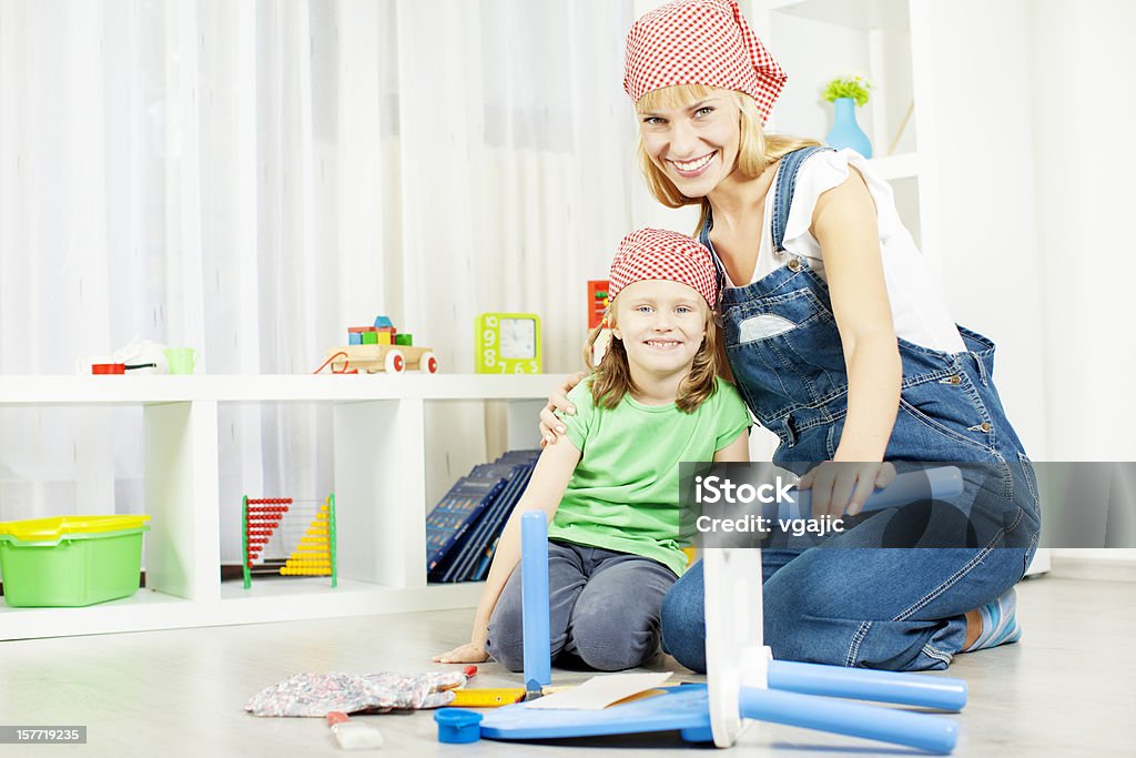 Happy Young Family Repair Furniture at home. Beautiful smiling young woman with her daughter repair furniture at home, repair children chair together. Activity Stock Photo