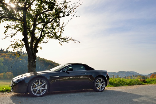 Heppenheim, Germany - October 20, 2012: Black Aston Martin V8 Vantage parked along a road through the hills near the town of Heppenheim in Germany during the autumn.